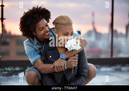 Loving couple with flowers on rooftop during sunset Stock Photo