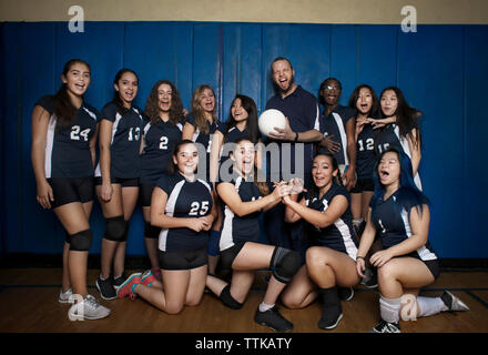 Happy volleyball team shouting against blue wall Stock Photo