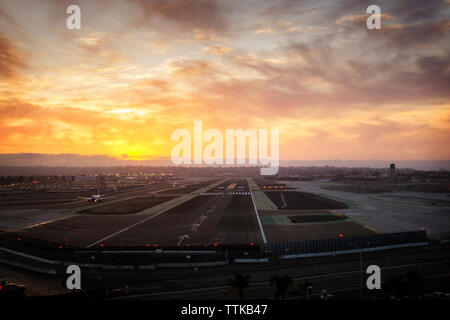 Airport runway against cloudy sky during sunset Stock Photo