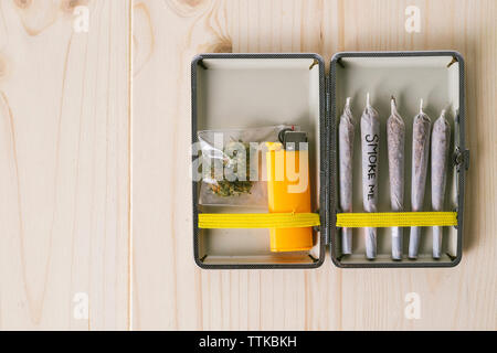 Overhead view of marijuana joints with cigarette lighter in container on table Stock Photo