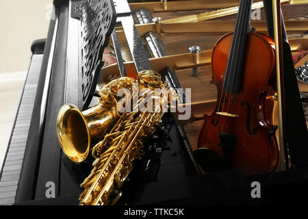 Violin and saxophone lying on piano, close up Stock Photo
