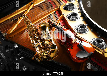 Violin and saxophone lying on piano, close up Stock Photo