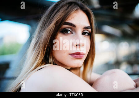 Side view portrait of confident young woman sitting in old factory Stock Photo