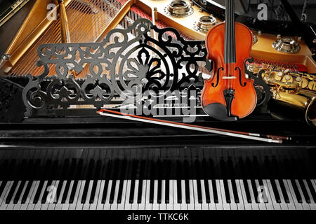 Violin and saxophone lying on piano, close up Stock Photo