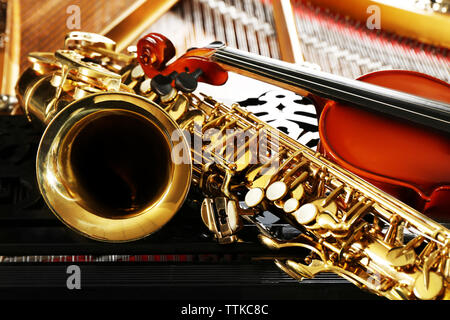 Violin and saxophone lying on piano, close up Stock Photo