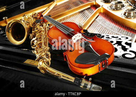 Violin and saxophone lying on piano, close up Stock Photo