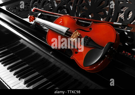 Violin lying on piano, close up Stock Photo