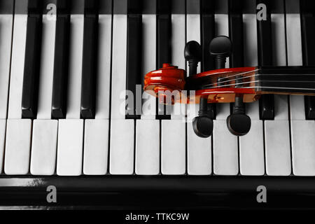 Violin neck lying on piano keys, close up Stock Photo