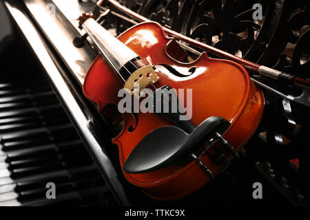Violin lying on piano, close up Stock Photo