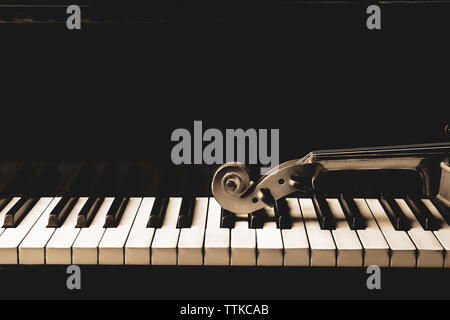 Violin neck lying on piano keys, close up Stock Photo