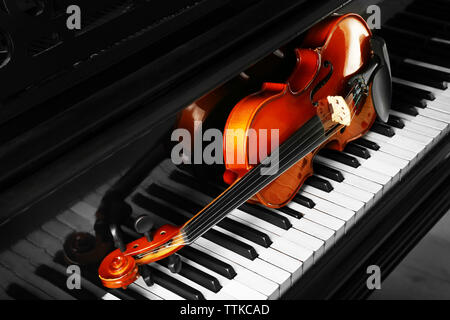 Violin lying on piano keys, close up Stock Photo