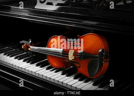 Violin lying on piano keys, close up Stock Photo