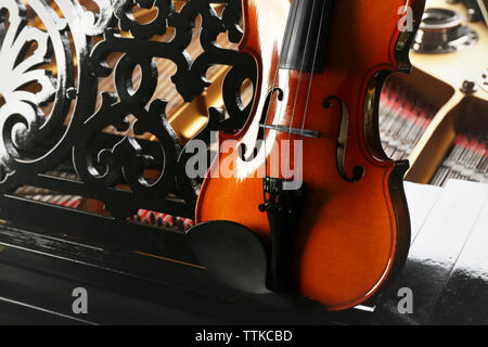 Violin lying on piano, close up Stock Photo