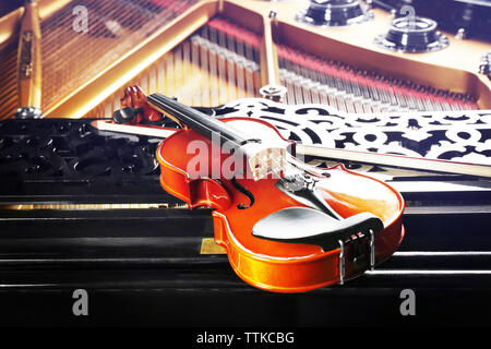Violin lying on piano, close up Stock Photo
