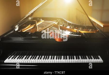 Violin lying on piano, close up Stock Photo
