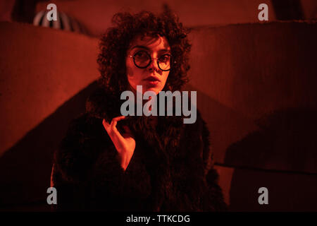 curly woman in glasses at night under a lantern Stock Photo