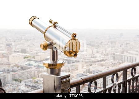 Coin-operated binocular on railing by cityscape against clear sky Stock Photo