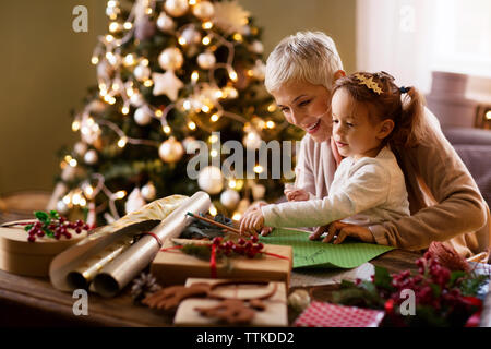 Grandmother assisting granddaughter in drawing at home Stock Photo