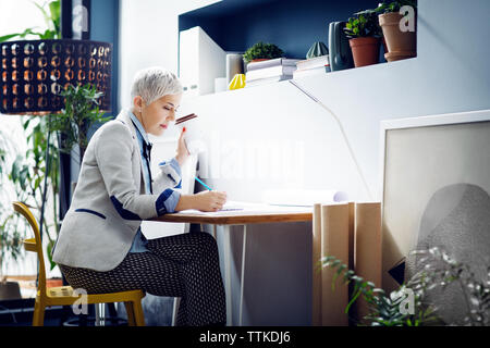 Female architect working while having coffee in office Stock Photo