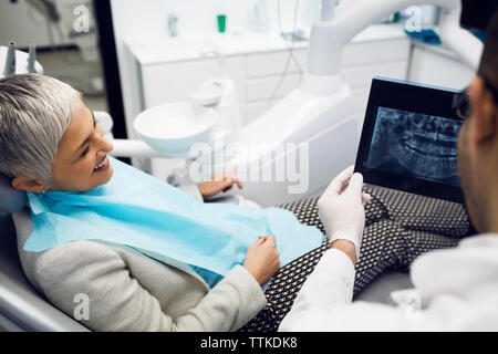 Dentist showing x-ray to happy woman at clinic Stock Photo