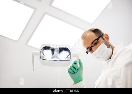Low angle view of dentist adjusting lamp in clinic Stock Photo