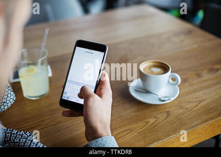 Cropped image of man text messaging through smart phone in cafe Stock Photo