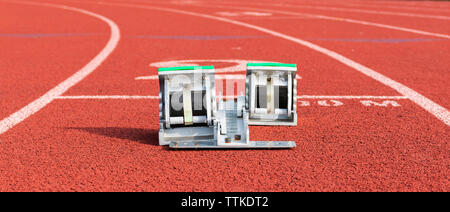 View from behind of a set of starting blocks in lane two on a red track. Stock Photo