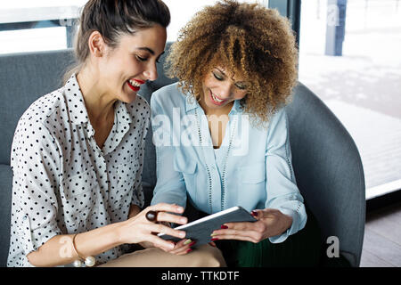 Cheerful female colleagues using tablet computer at cafe Stock Photo