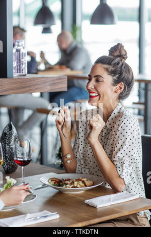 Cheerful businesswoman looking at colleague while having lunch at restaurant Stock Photo