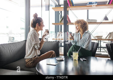 Happy businesswomen discussing while having coffee at cafe Stock Photo