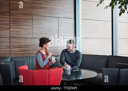 Cheerful business couple enjoying drinks while sitting in restaurant Stock Photo