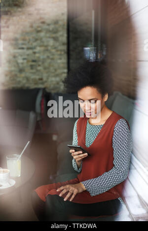 businesswoman using smart phone while sitting on sofa at cafe Stock Photo