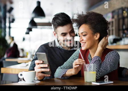 Happy business couple using mobile phone in cafe Stock Photo