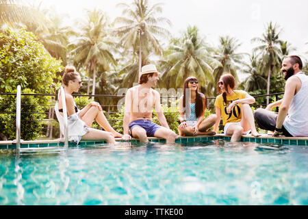 Cheerful friends spending leisure time at poolside Stock Photo