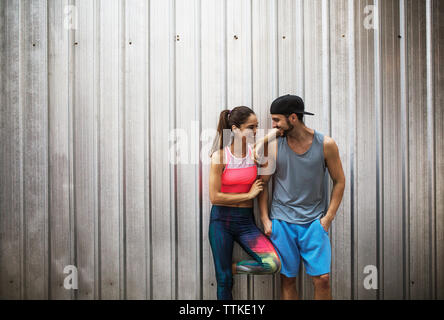 Happy couple standing against metallic wall Stock Photo