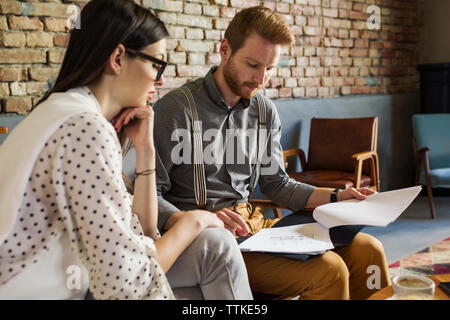 Businessman and businesswoman analyzing documents at hotel lobby Stock Photo