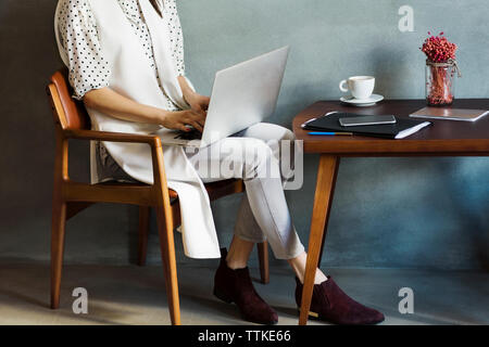 Low section of businesswoman using laptop at hotel lobby Stock Photo
