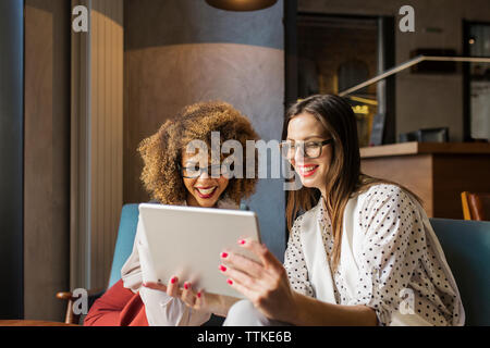 Happy businesswomen using tablet computer at hotel lobby Stock Photo
