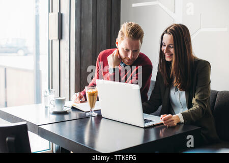 Happy business couple using laptop in restaurant Stock Photo