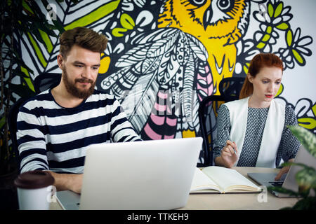 business people using laptops at desk in creative office Stock Photo
