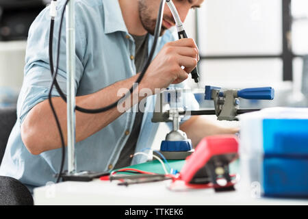 Engineer using drill on circuit board in electronic laboratory Stock Photo
