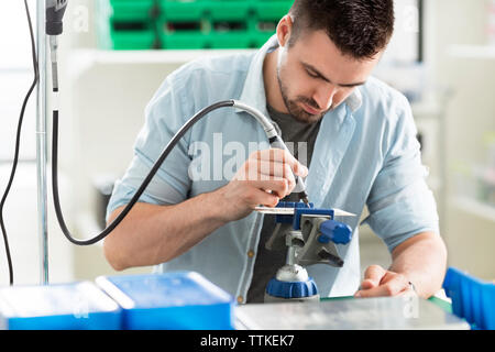 Concentrated engineer working on circuit board in electronic laboratory Stock Photo