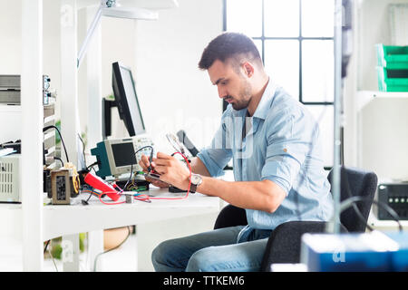 Serious engineer working at table in electronics laboratory Stock Photo