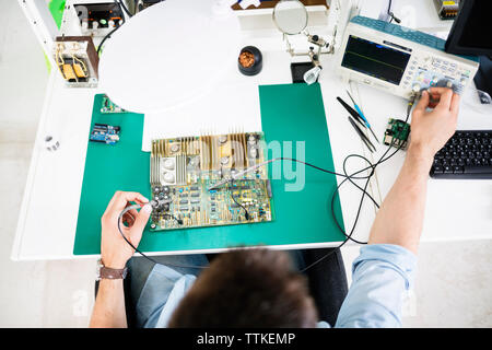 High angle view of technician checking circuit board at table in electronics industry Stock Photo