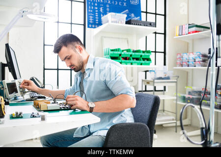 Concentrated technician soldering circuit board at table in electronics industry Stock Photo