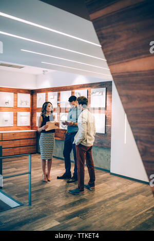 Happy business people discussing while standing in office Stock Photo