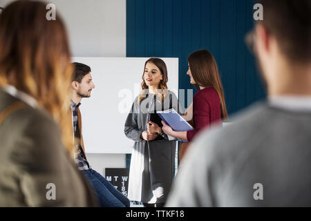 College students talking while standing in classroom Stock Photo