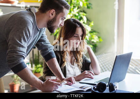 Friends using laptop computer while sitting at table in college Stock Photo