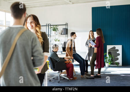 Friends talking while standing at table in classroom Stock Photo