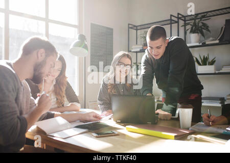 Friends discussing while studying in classroom Stock Photo